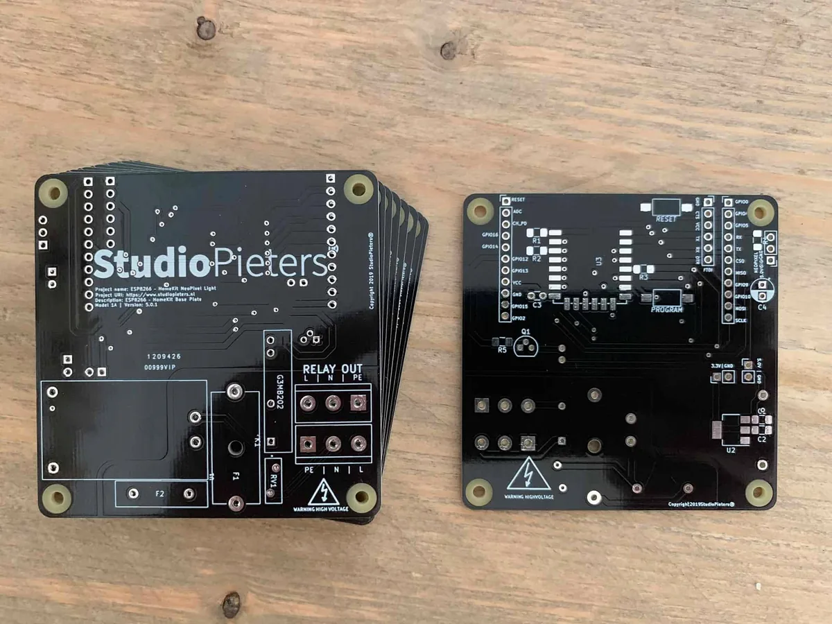 A stack of bare black printed circuit boards next to one board turned over
