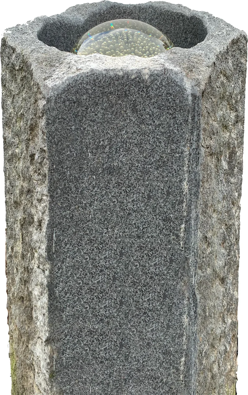 A granite column water feature with a clear dish on top