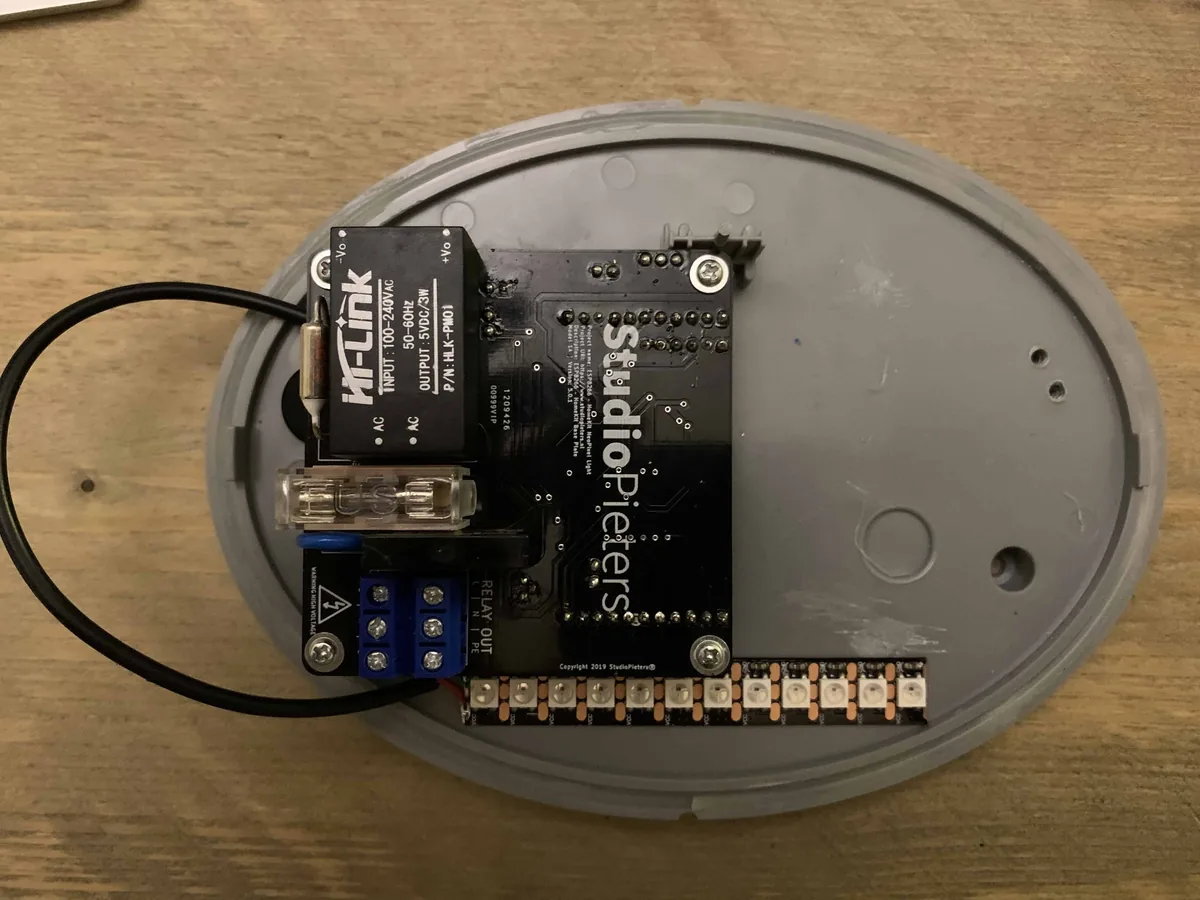 The controller board with the power module, fuse holder and screw terminals in the base of the fixture, with the NeoPixel strip along its edge
