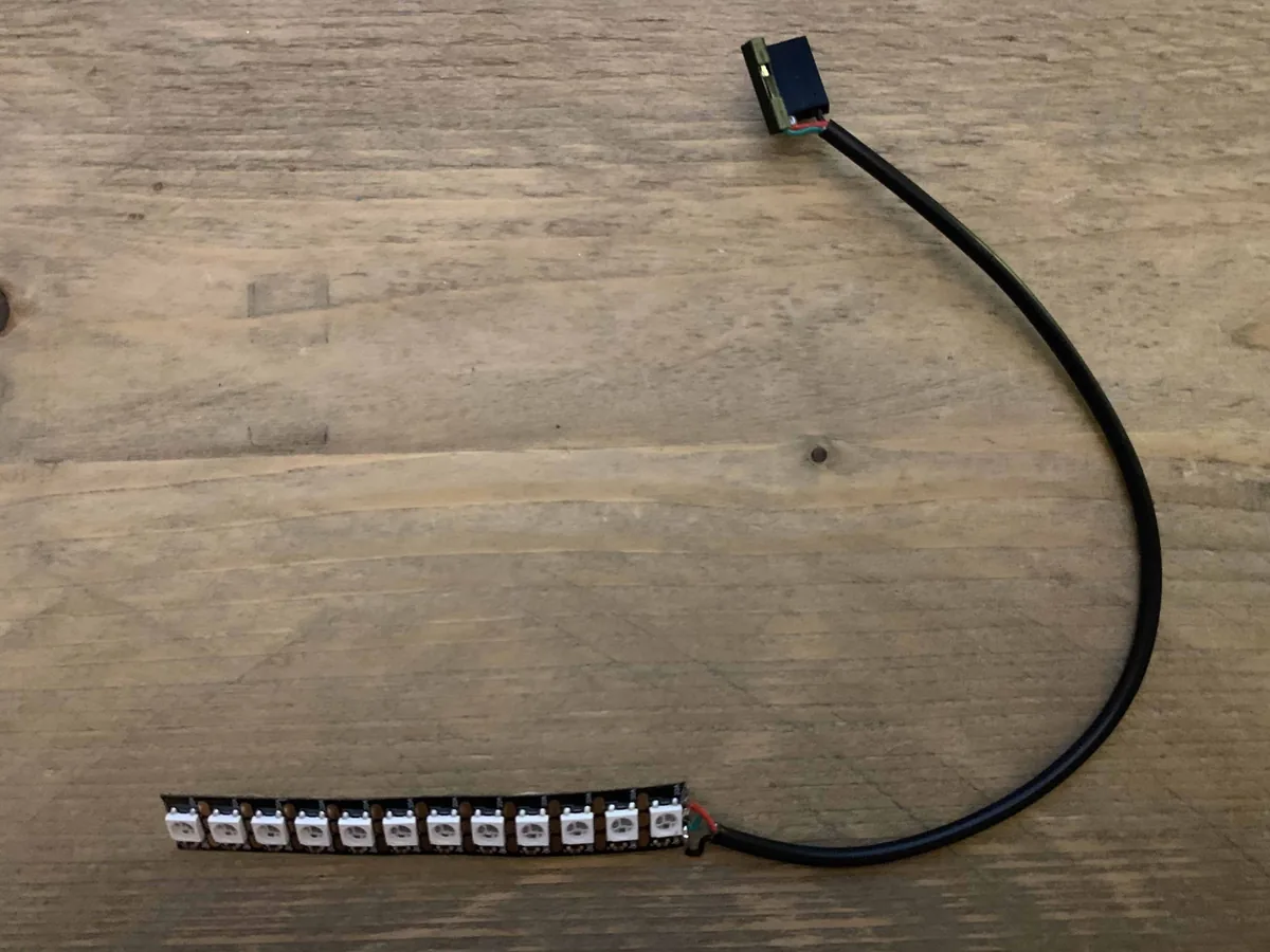 A NeoPixel strip with twelve LEDs on a black cable