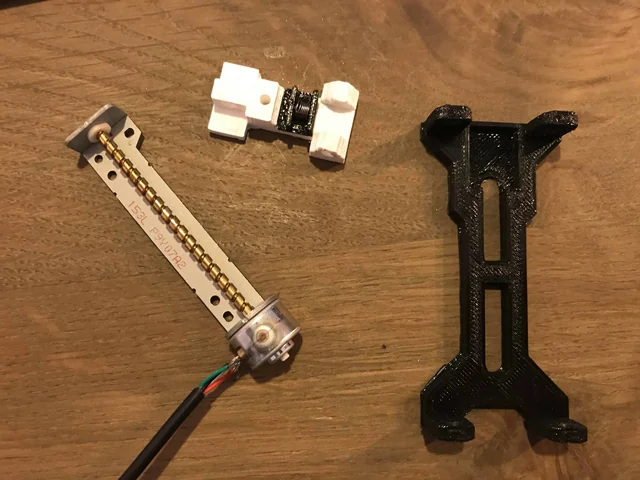 A stepper motor with a threaded rod next to a black printed part
