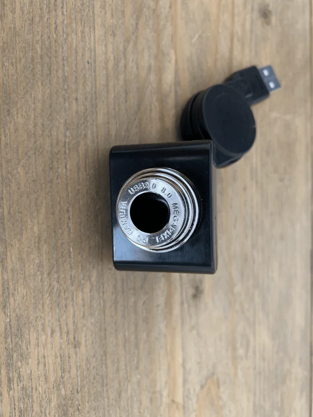 A small black USB camera on a wooden table